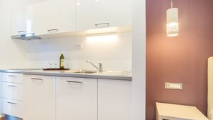 A modern kitchen with white cabinets, a stainless steel sink, and a wine bottle on the counter. - Beachfront Villa Mediteran (Podstrana)