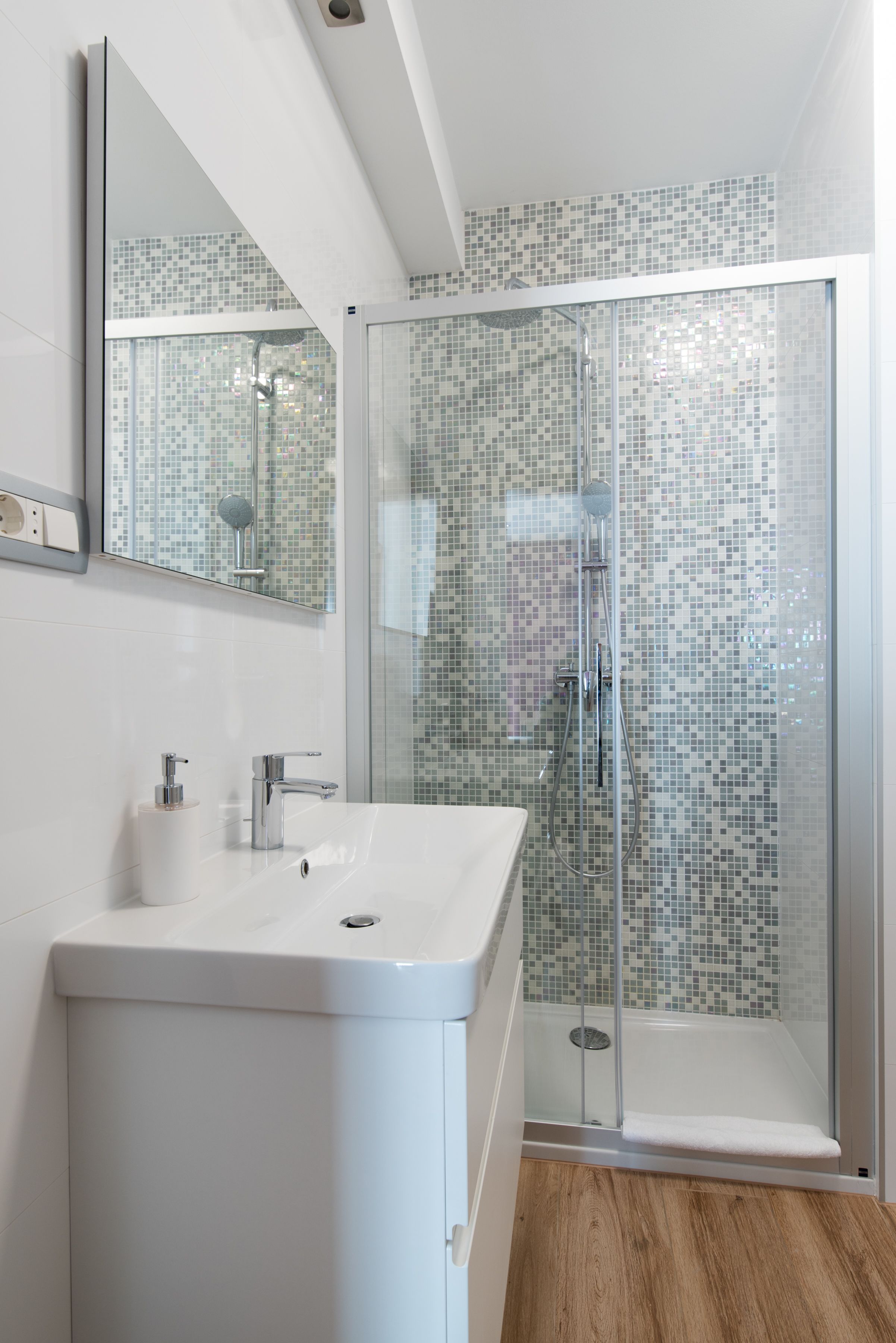 A modern bathroom with a glass-enclosed shower, a white sink, and a tiled backsplash.