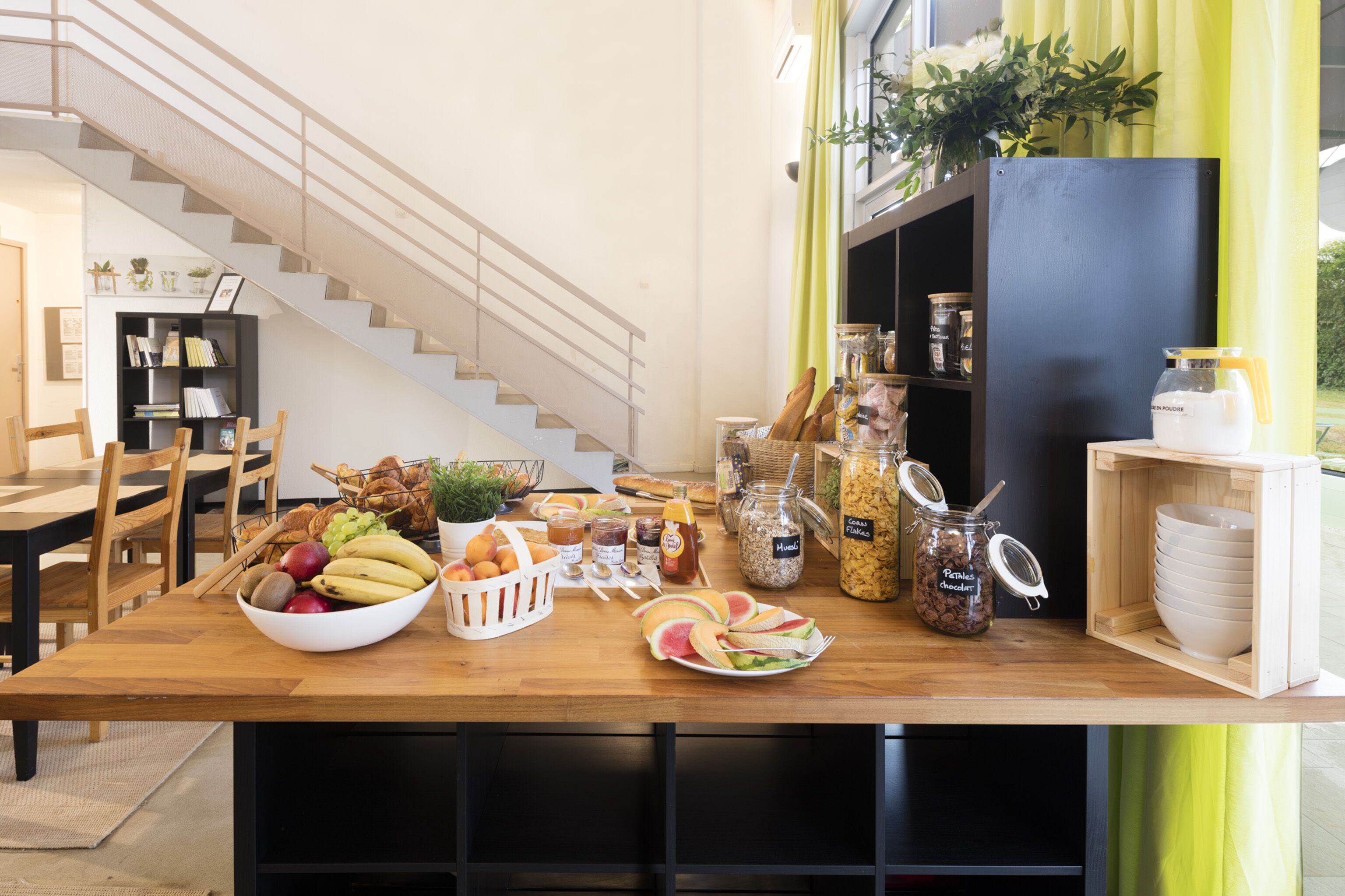 A breakfast buffet with a variety of fruits, breads, and spreads on a wooden table.