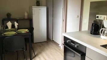 Una cocina compacta equipada con refrigerador, cafetera y microondas.