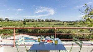 Una mesa con vista a una piscina y campos verdes.
