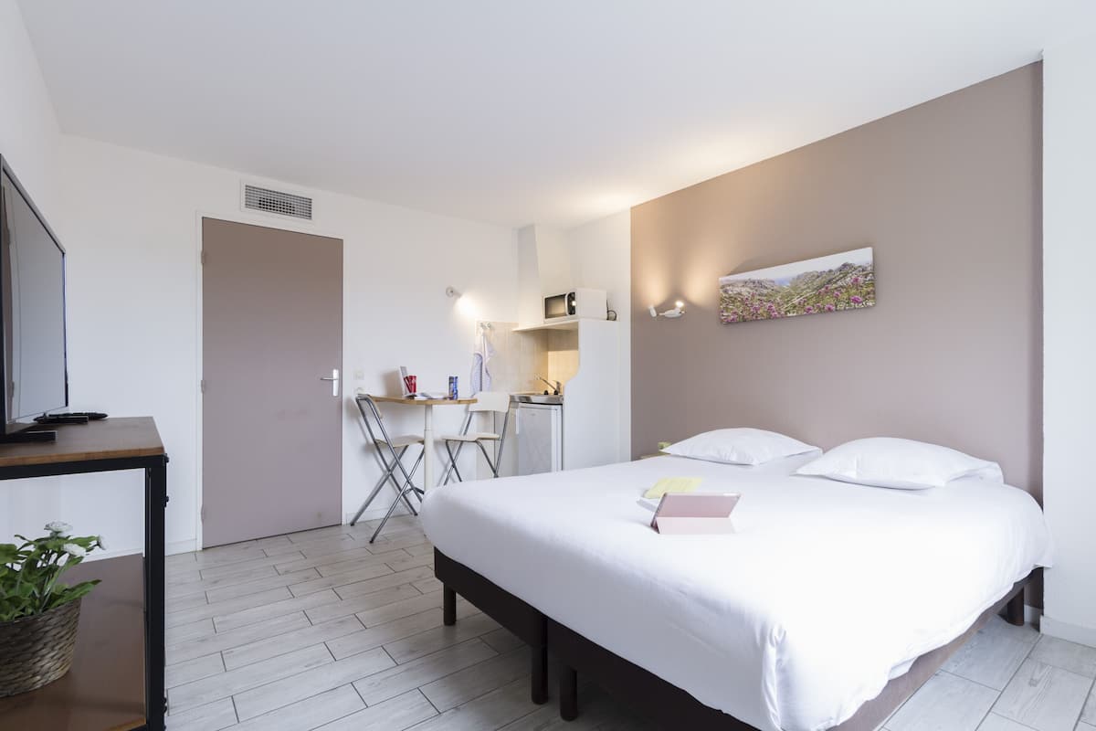 Un dormitorio con cama, escritorio, silla y televisor.