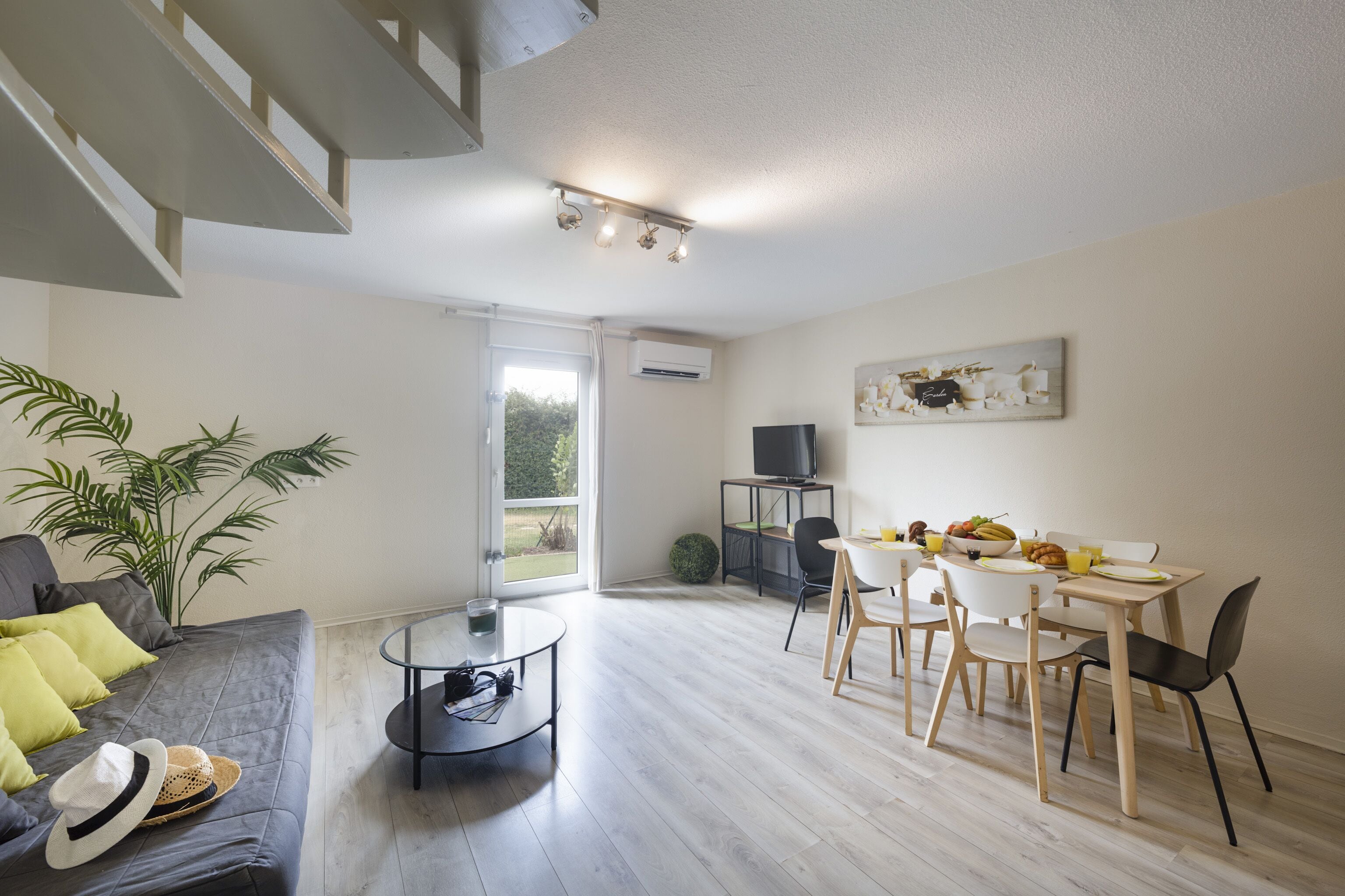 Un salon moderne comprenant un canapé, une table basse et un coin repas avec des chaises et une table.