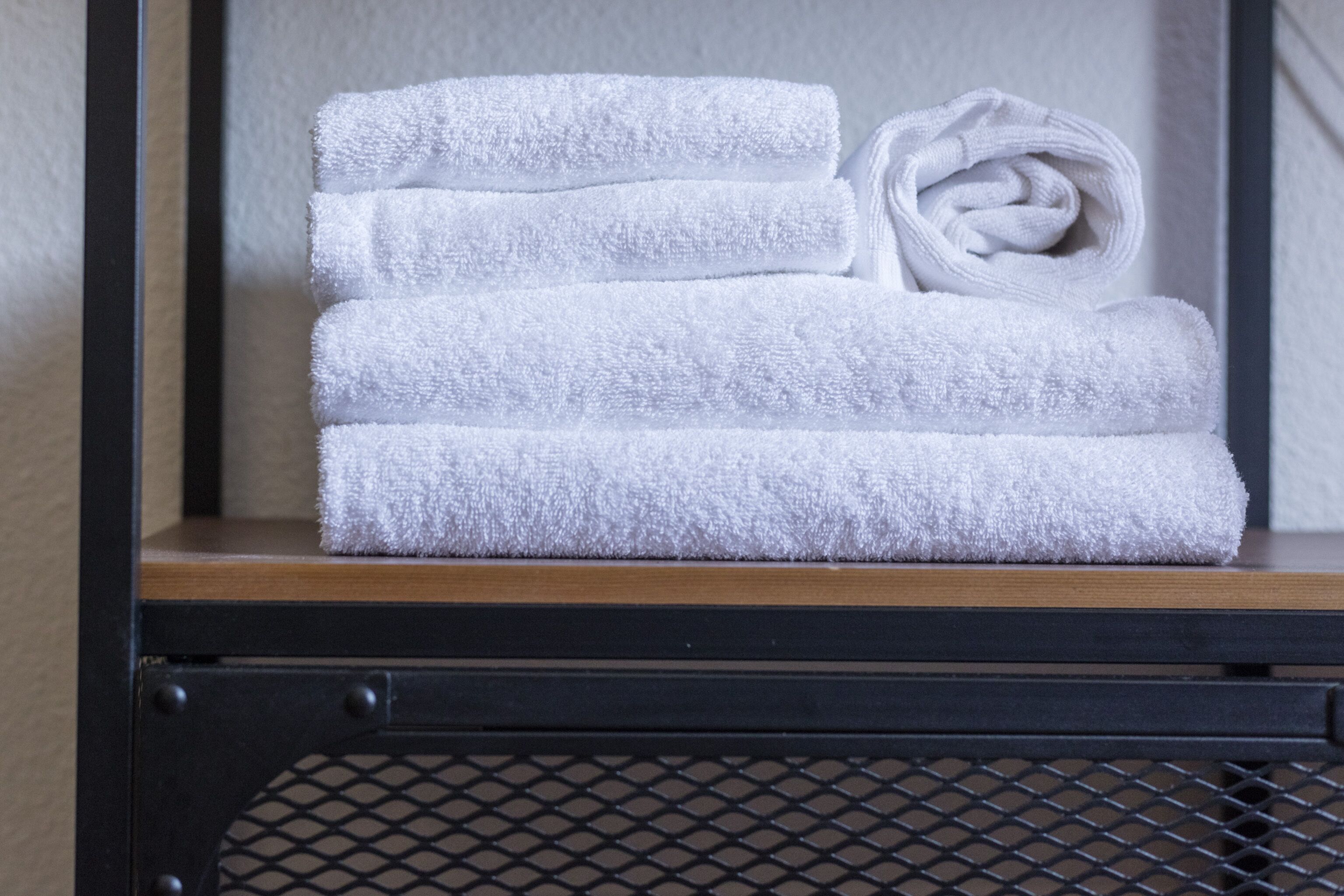 A stack of white towels on a wooden shelf.