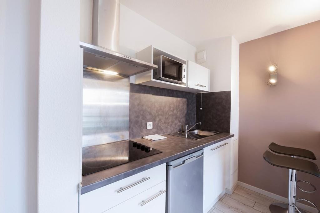 Una cocina compacta equipada con microondas, estufa, lavaplatos y pileta.
