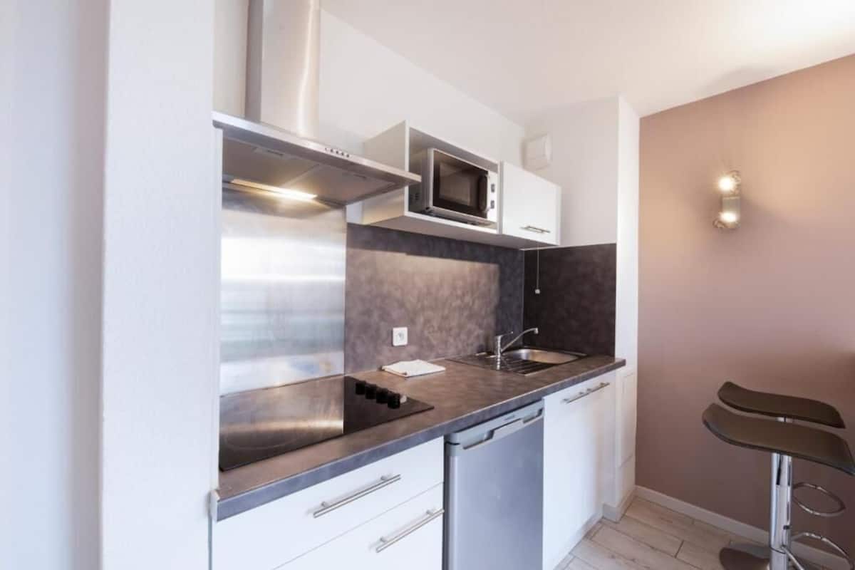 Una cocina compacta equipada con microondas, estufa, lavaplatos y pileta.