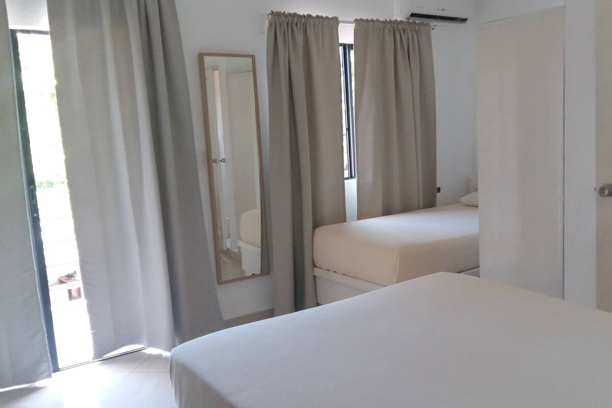 Une chambre avec un lit simple, un grand miroir et une porte.