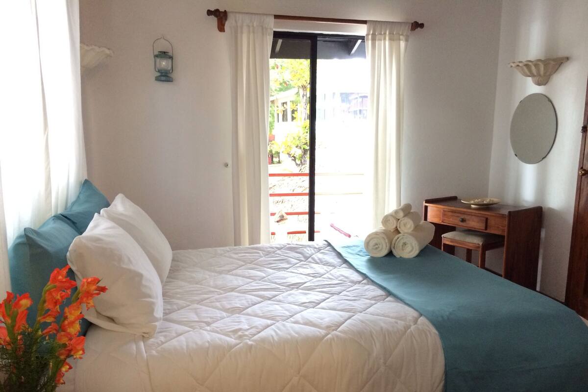 Une chambre à coucher avec un lit, une commode, un miroir et une fenêtre avec des rideaux.