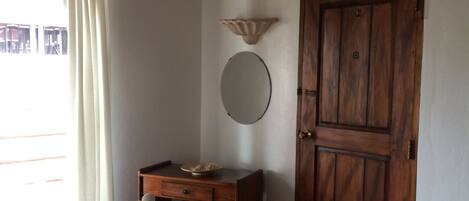 Un dormitorio con una cama, un aparador de madera, un televisor en la pared y una puerta.