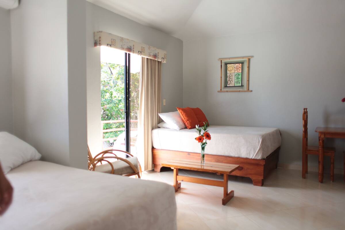 Une chambre à coucher avec un lit, une table de chevet en bois, une chaise et une fenêtre avec des rideaux.