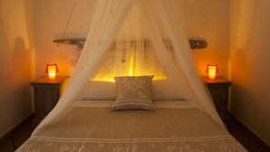 A bed with a canopy, two bedside lamps, and a wall-mounted shelf with a starfish decoration. - AgriRistoChic Resort Li Espi (Palau)