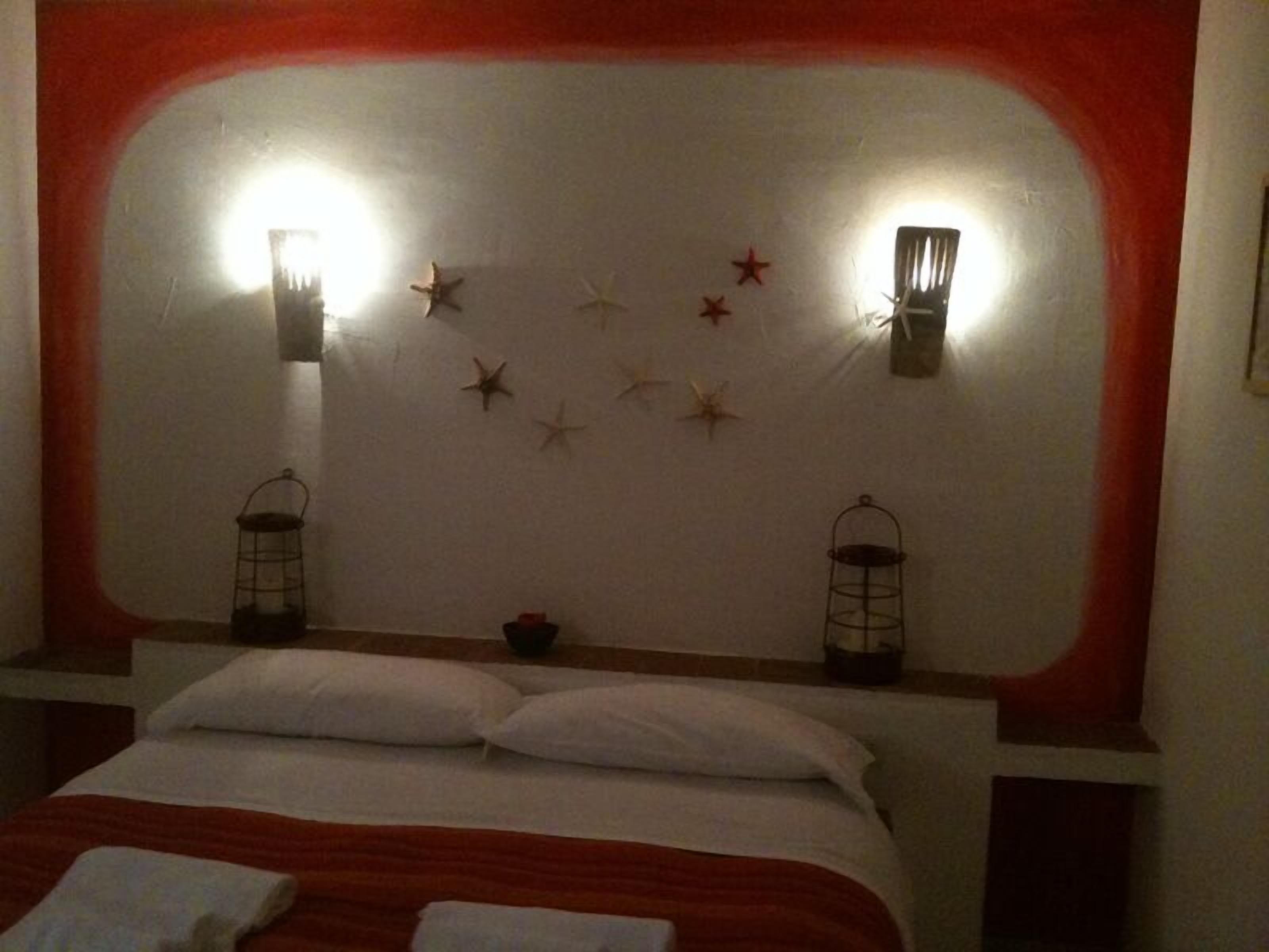 A bedroom with a bed, two wall-mounted lanterns, and star decorations on the wall.