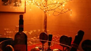 A bar area with a tree-like light decoration, bottles, and glasses on a table. - AgriRistoChic Resort Li Espi (Palau)
