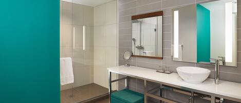 Un baño moderno con cabina de ducha de vidrio, un lavamanos blanco y un espejo grande.