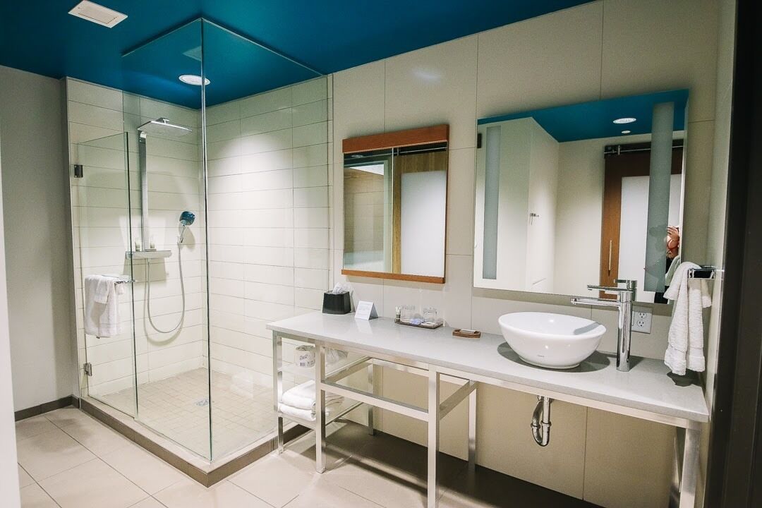 A modern bathroom with a glass-enclosed shower, a white sink, and a large mirror.