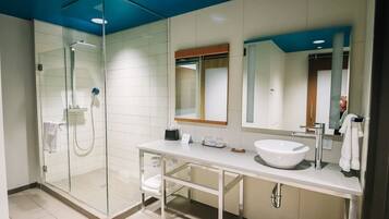 A modern bathroom with a glass-enclosed shower, a white sink, and a large mirror.