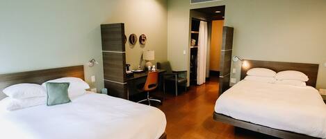 A hotel room with two beds, a desk, a chair, and a wardrobe.
