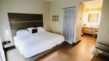 A hotel room with a large bed, bedside table, and a bathroom with a mirror and sink.