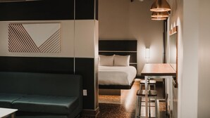 Ein modernes Hotelzimmer mit einem Bett, einer Couch, einem Esstisch und einer Pendelleuchte.