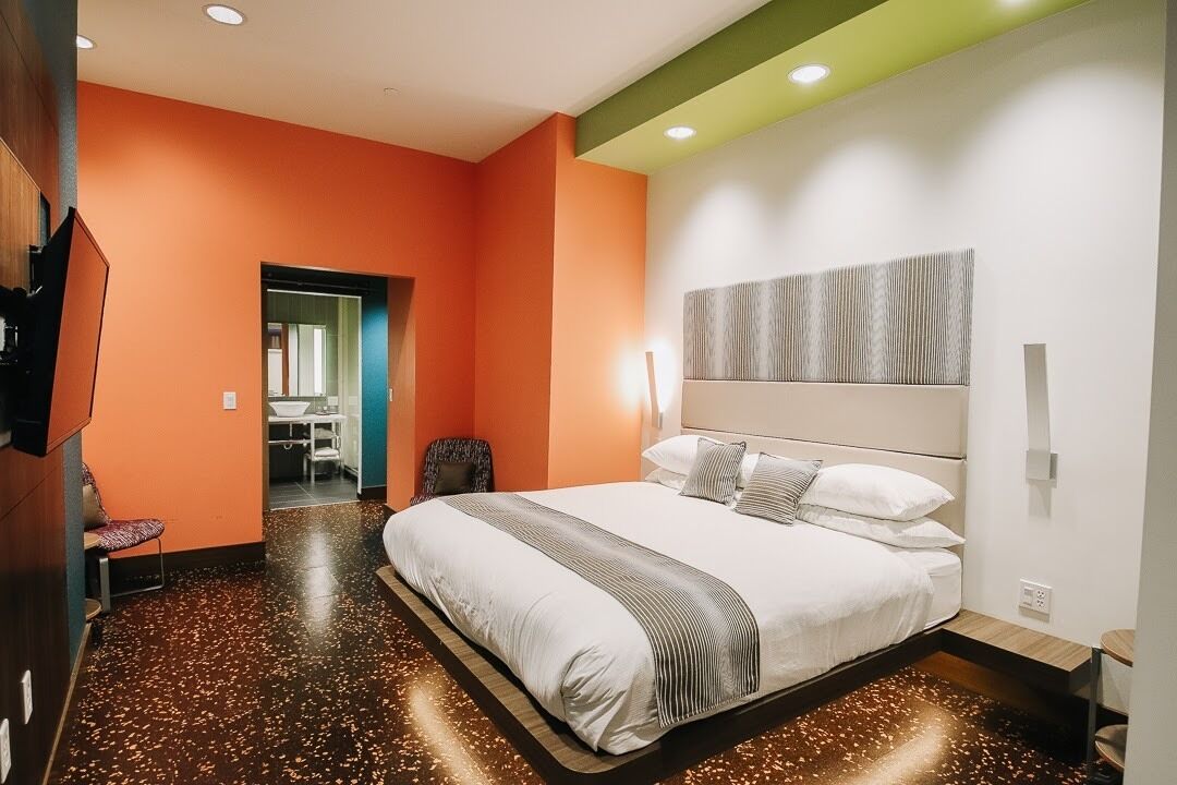 A modern hotel room with a large bed, a seating area, and a bathroom.