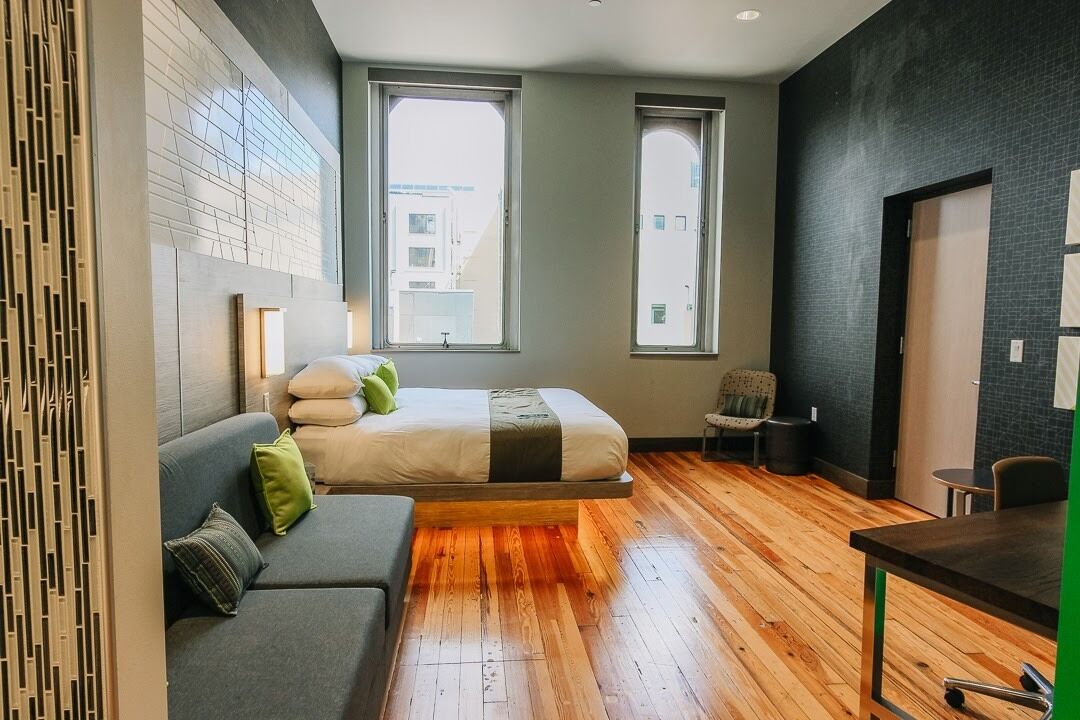 Une chambre moderne équipée d’un lit, d’un canapé, d’un bureau et de deux fenêtres.