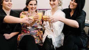 Four people toasting with drinks, seated on a couch.