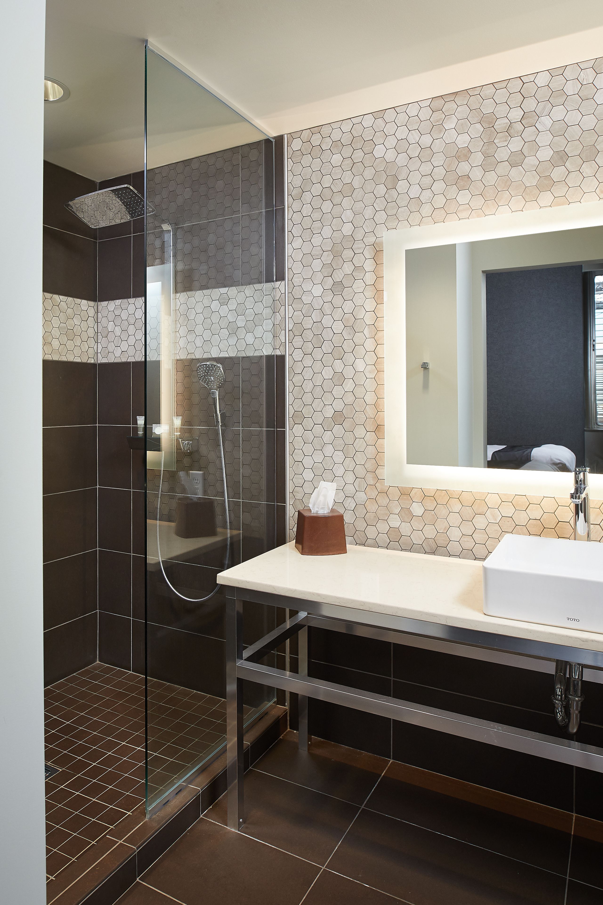 Une salle de bain moderne avec une douche à parois de verre, un grand miroir et un lavabo blanc.
