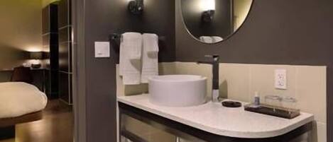 A modern bathroom with a round mirror, white sink, and a towel rack.