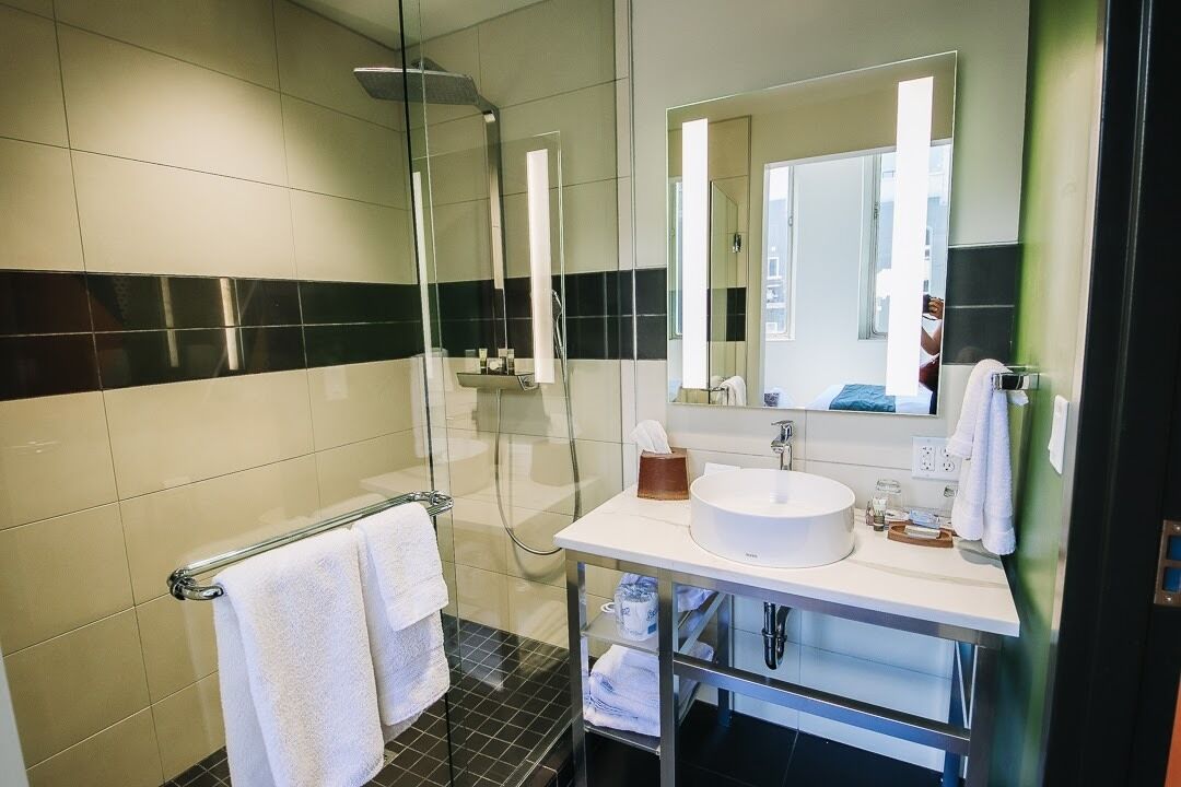 Een moderne badkamer met een douchecabine van glas, een witte wastafel en een grote spiegel.
