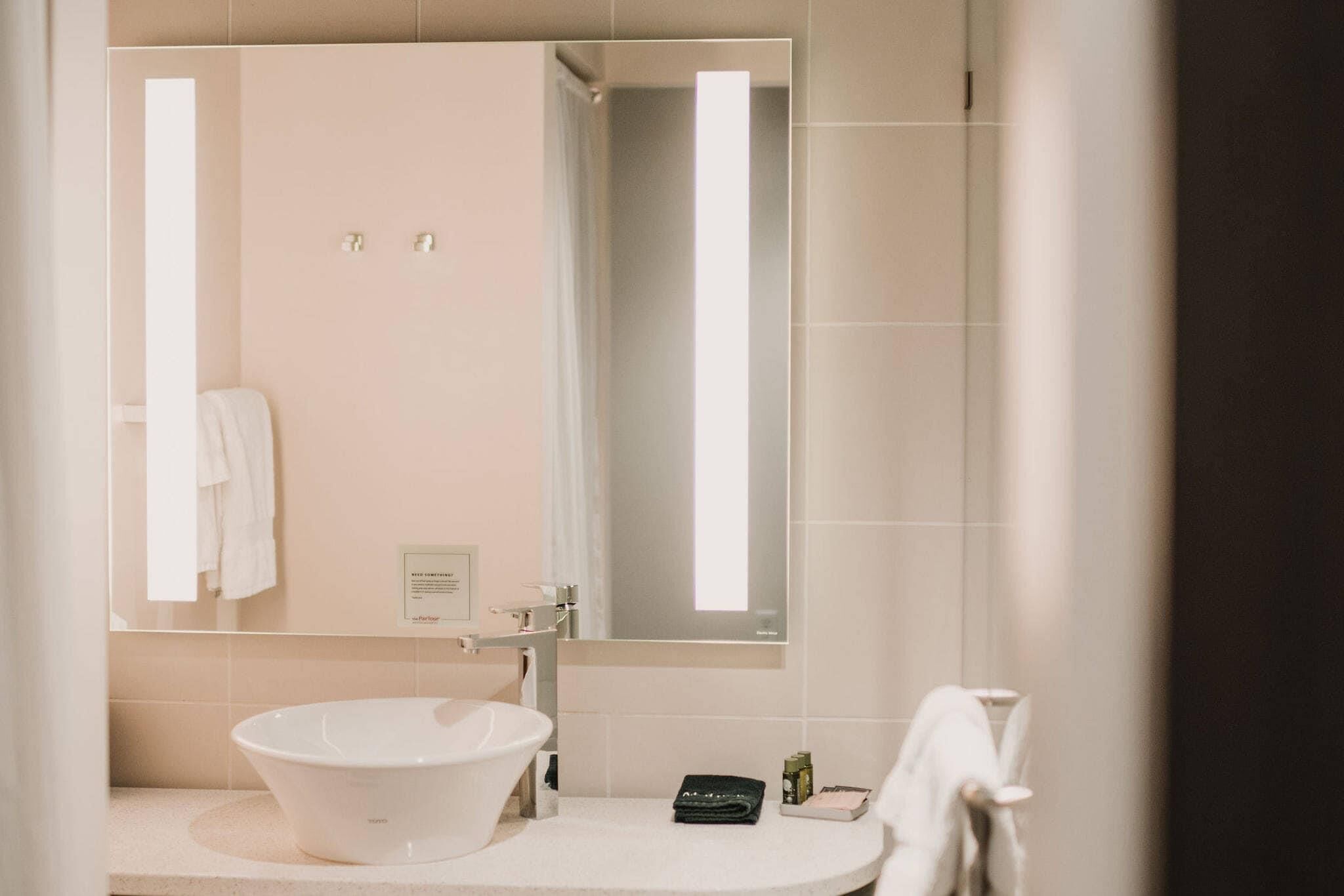 A bathroom with a large mirror, a white sink, and a towel rack.