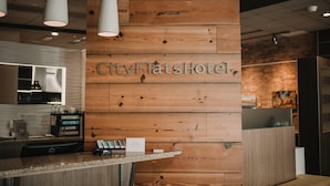 Eine Rezeption mit einer Holzwand, auf der der Name "CityFlatsHotel" steht.