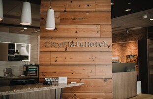 A reception desk with a wooden panel wall displaying the name "CityFlatsHotel".