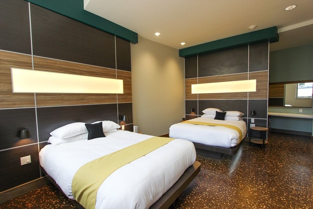Een hotelkamer met twee bedden, een grote spiegel en een modern design.