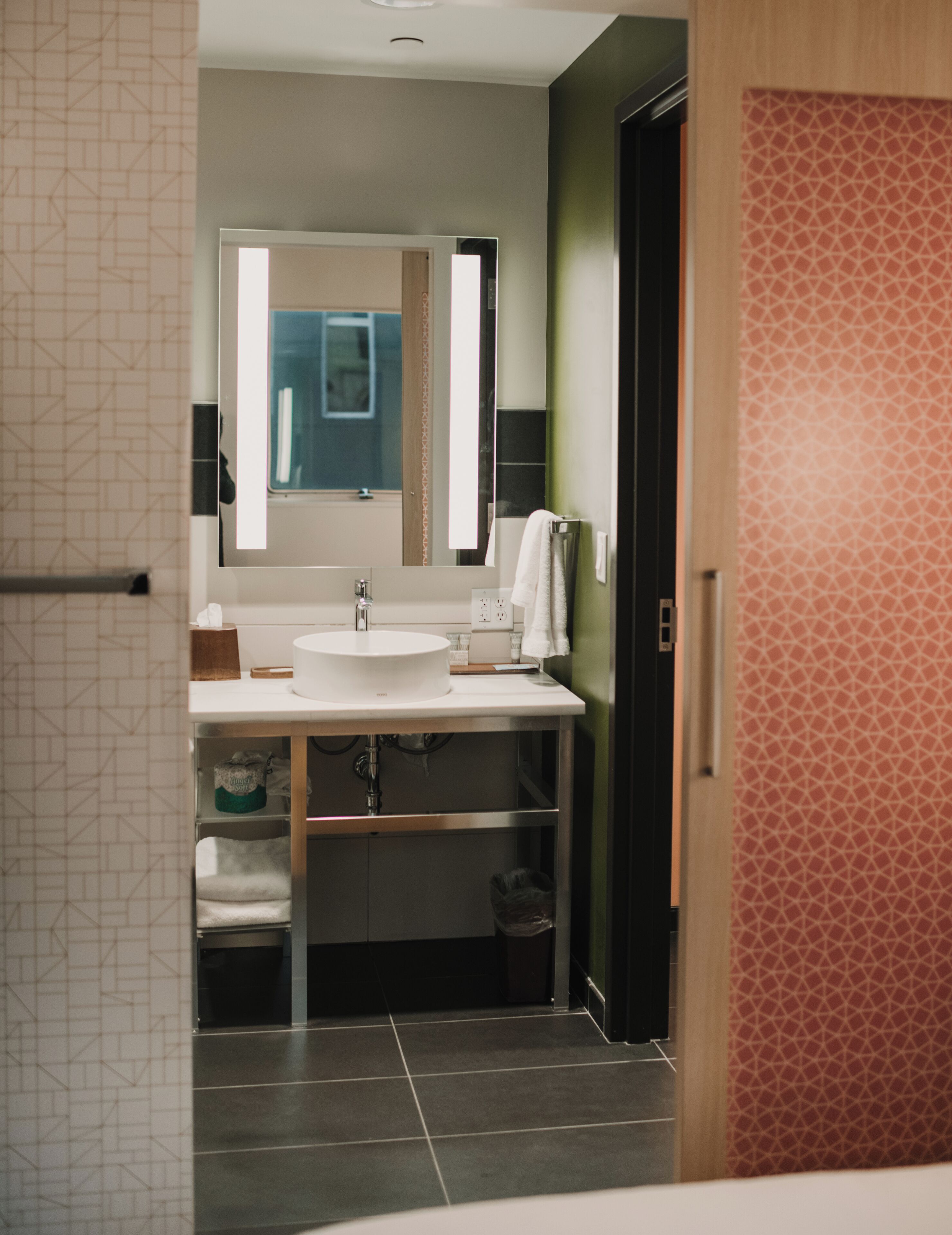 A modern bathroom with a white sink, a mirror, and a towel rack.