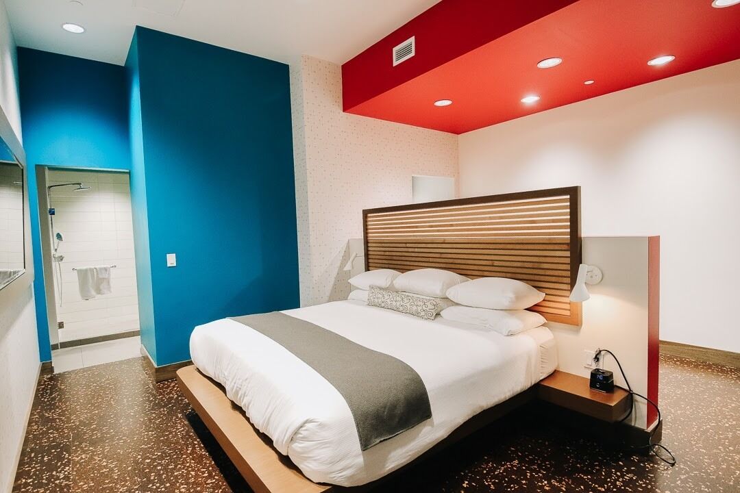 Une chambre d’hôtel moderne avec un grand lit, une table de chevet et un plafond rouge.