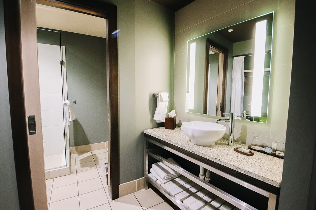 Ein modernes Badezimmer mit großem Waschbecken, Spiegel und Handtuchhalter.