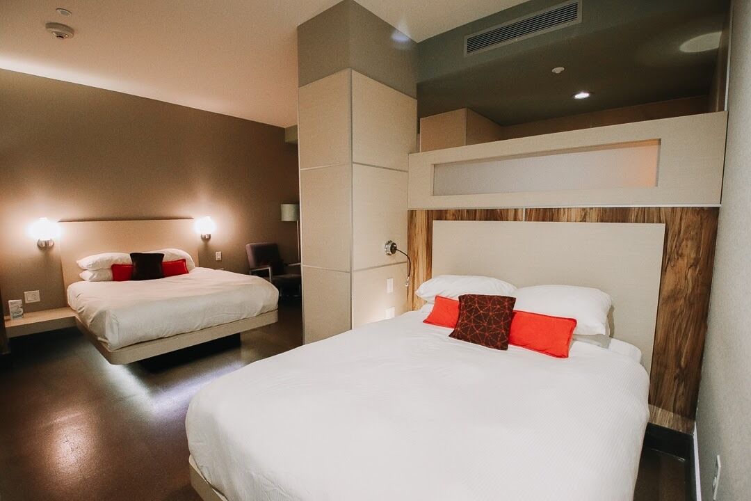 A hotel room with two beds, a wooden headboard, and a built-in wardrobe.