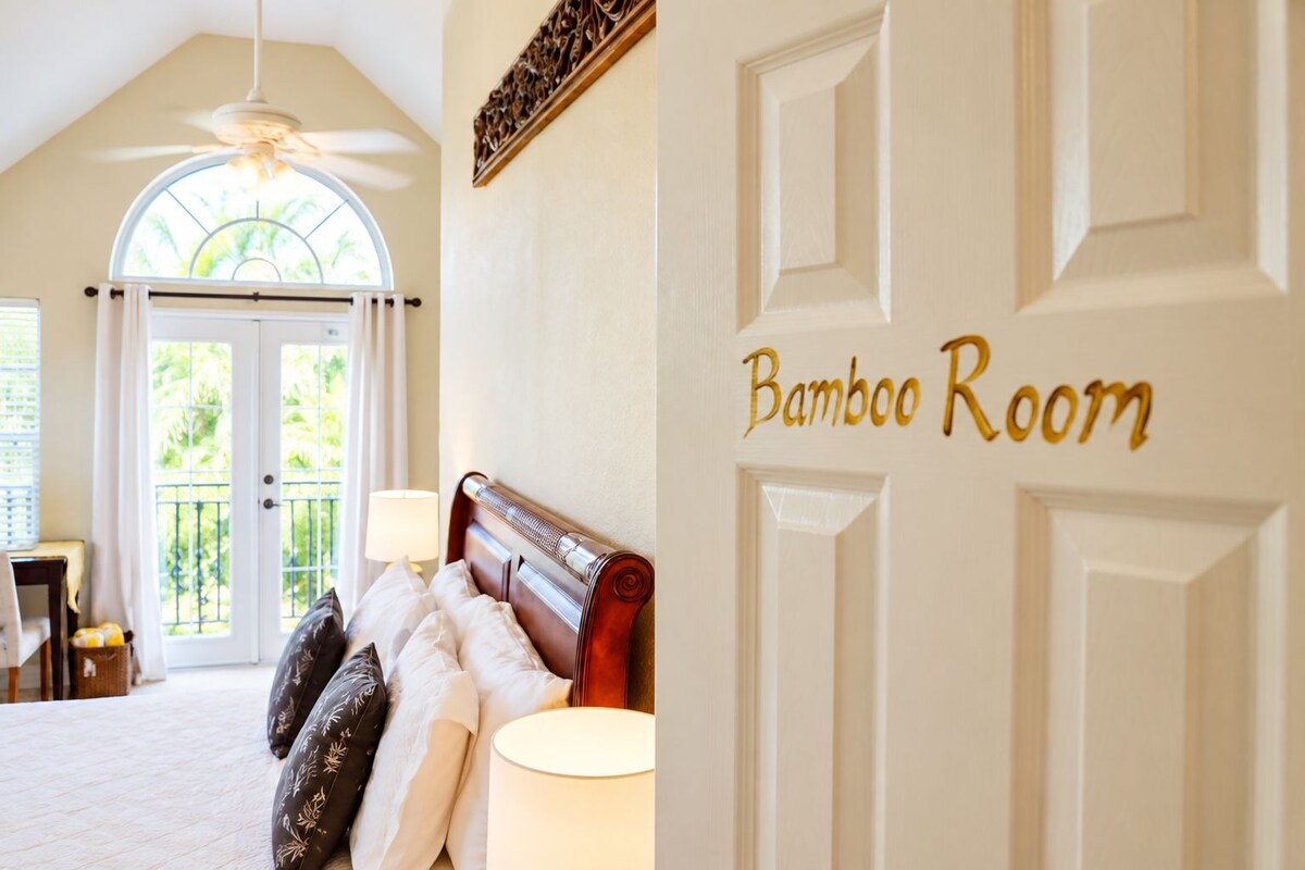 Ein Zimmer mit einem Bett, einer Lampe und einer Tür mit der Aufschrift 'Bamboo Room'.