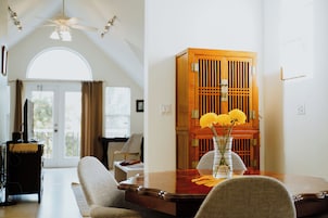 Una habitación con un armario de madera, un florero con flores, un escritorio y una silla.
