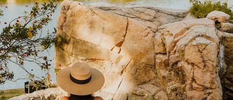 A person in a hot spring with a view of a building and palm trees.