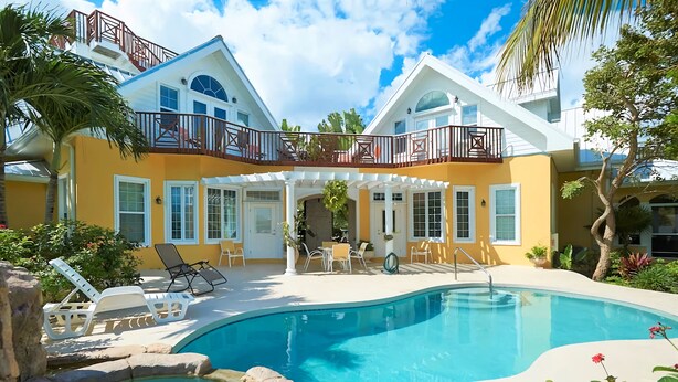 Une maison à deux étages dotée d’une piscine, de mobilier d’extérieur et d’un patio couvert.