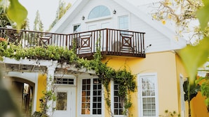 Une maison avec une piscine, un balcon orné de plantes et une porte blanche.