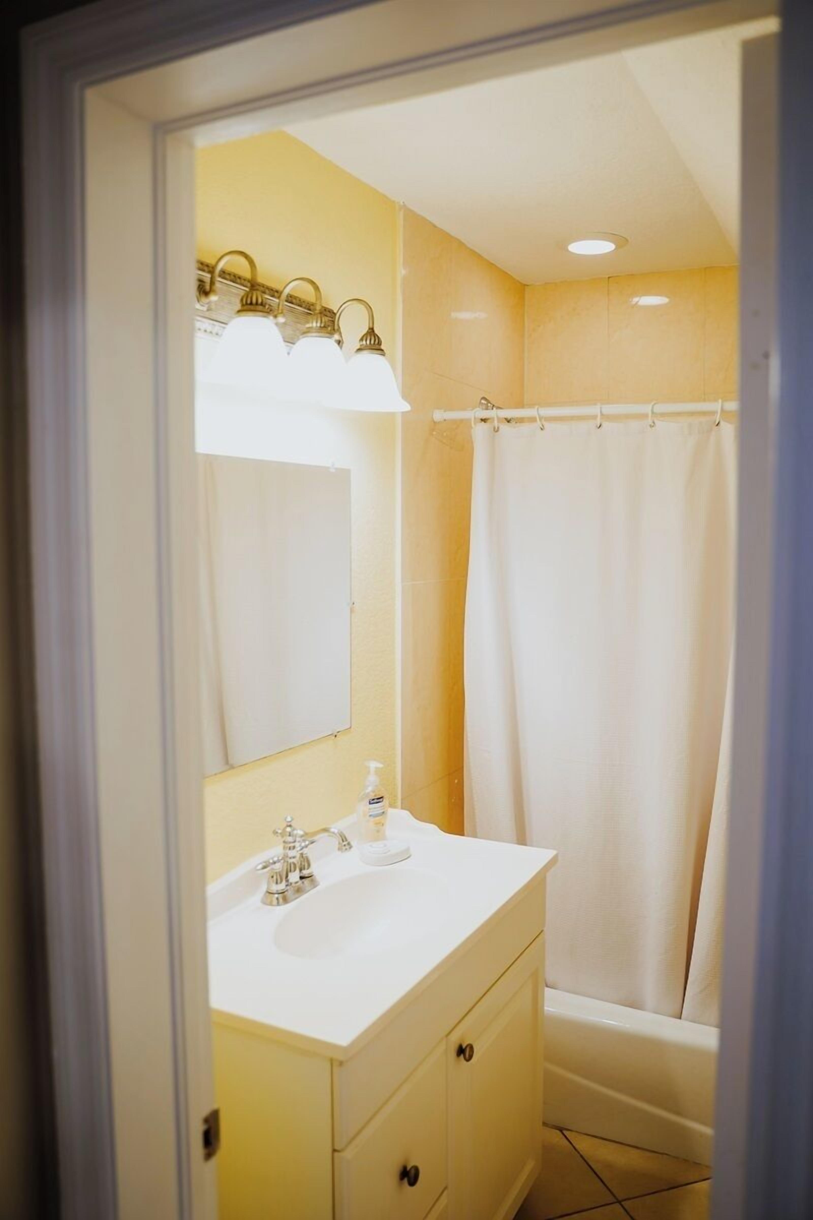 A bathroom with a white sink, mirror, and shower curtain.