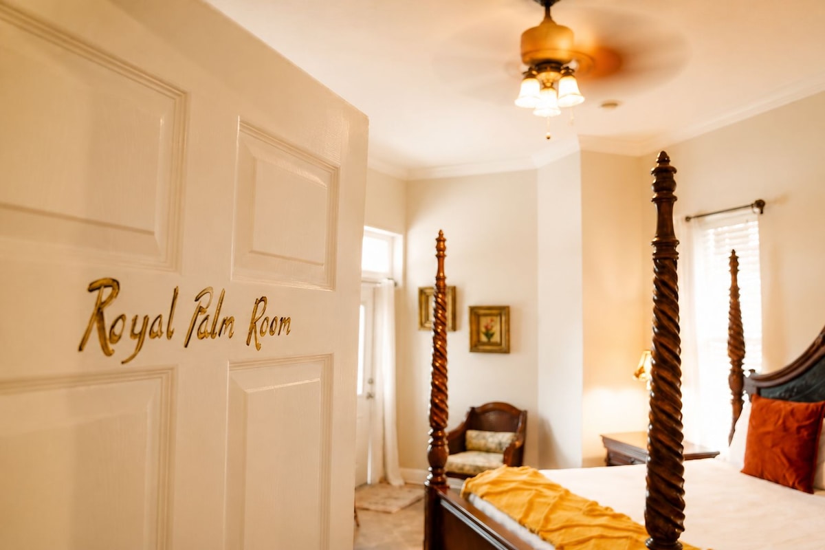 Ein Schlafzimmer mit einem Himmelbett, einem Deckenventilator und einer Tür mit der Aufschrift 'Royal Palm Room'.