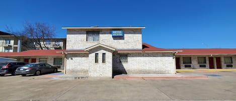 A motel with a red roof and a sign that reads "Motel Open 24 Hours."