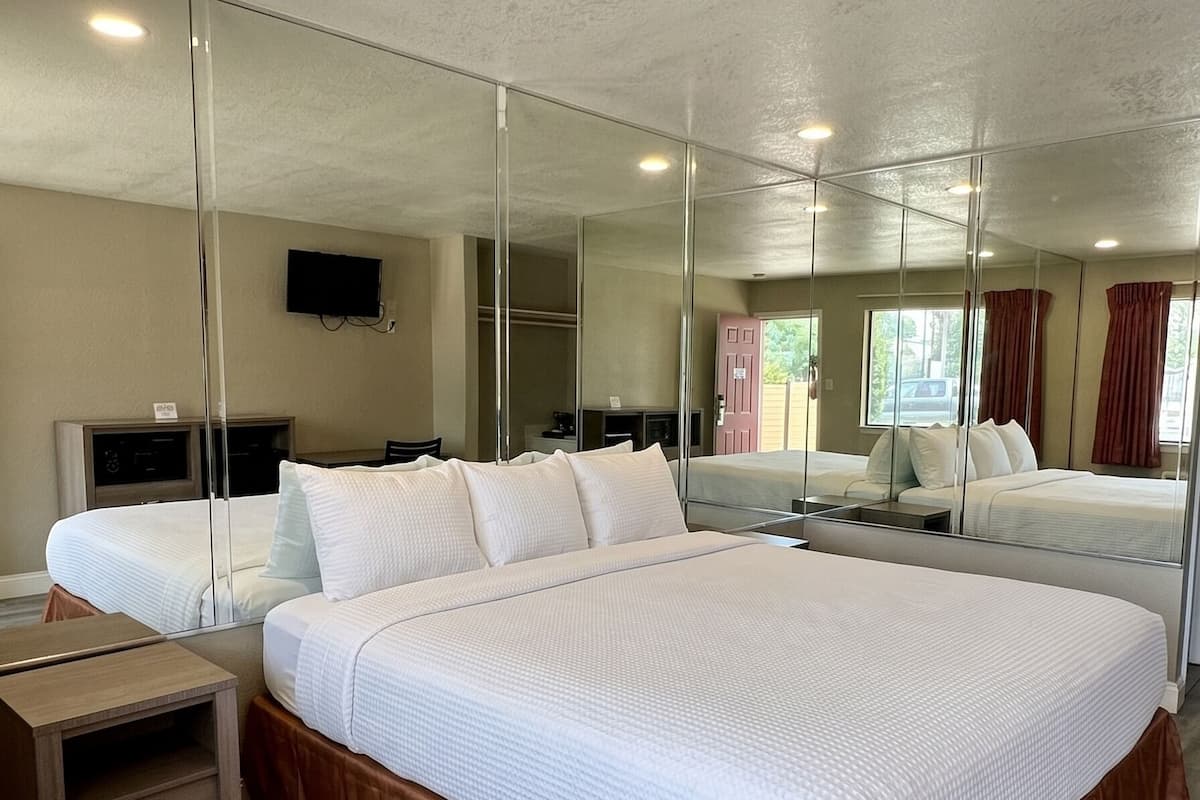 Quarto de hotel com uma cama grande, uma mesa de cabeceira de madeira, uma televisão e um espelho.