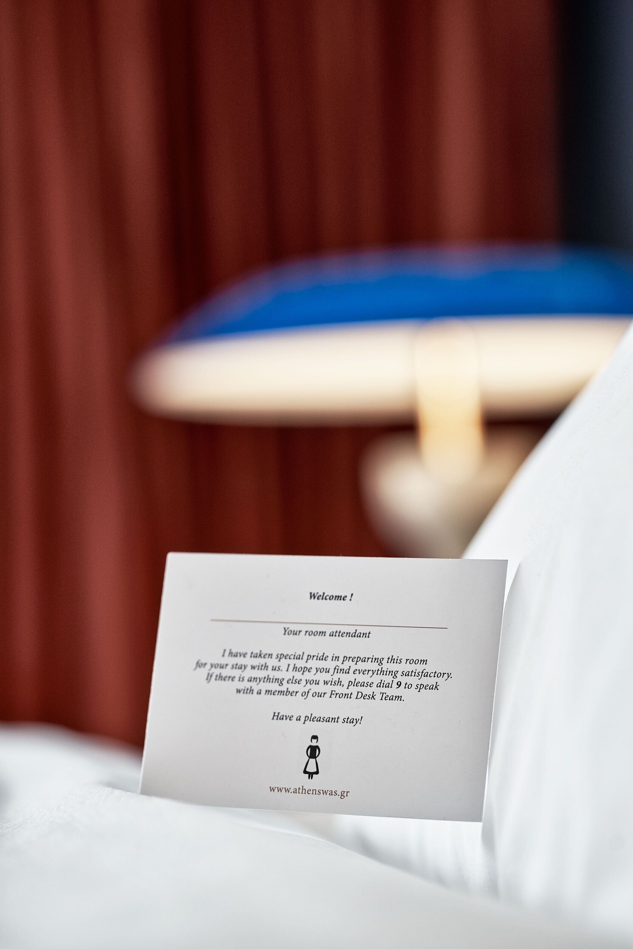 A welcome card on a bed with a blurred background of a room.