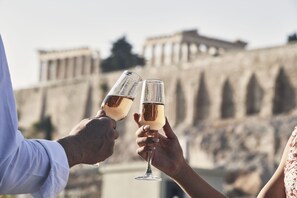 Two people toasting with champagne glasses in front of a historic building with columns.