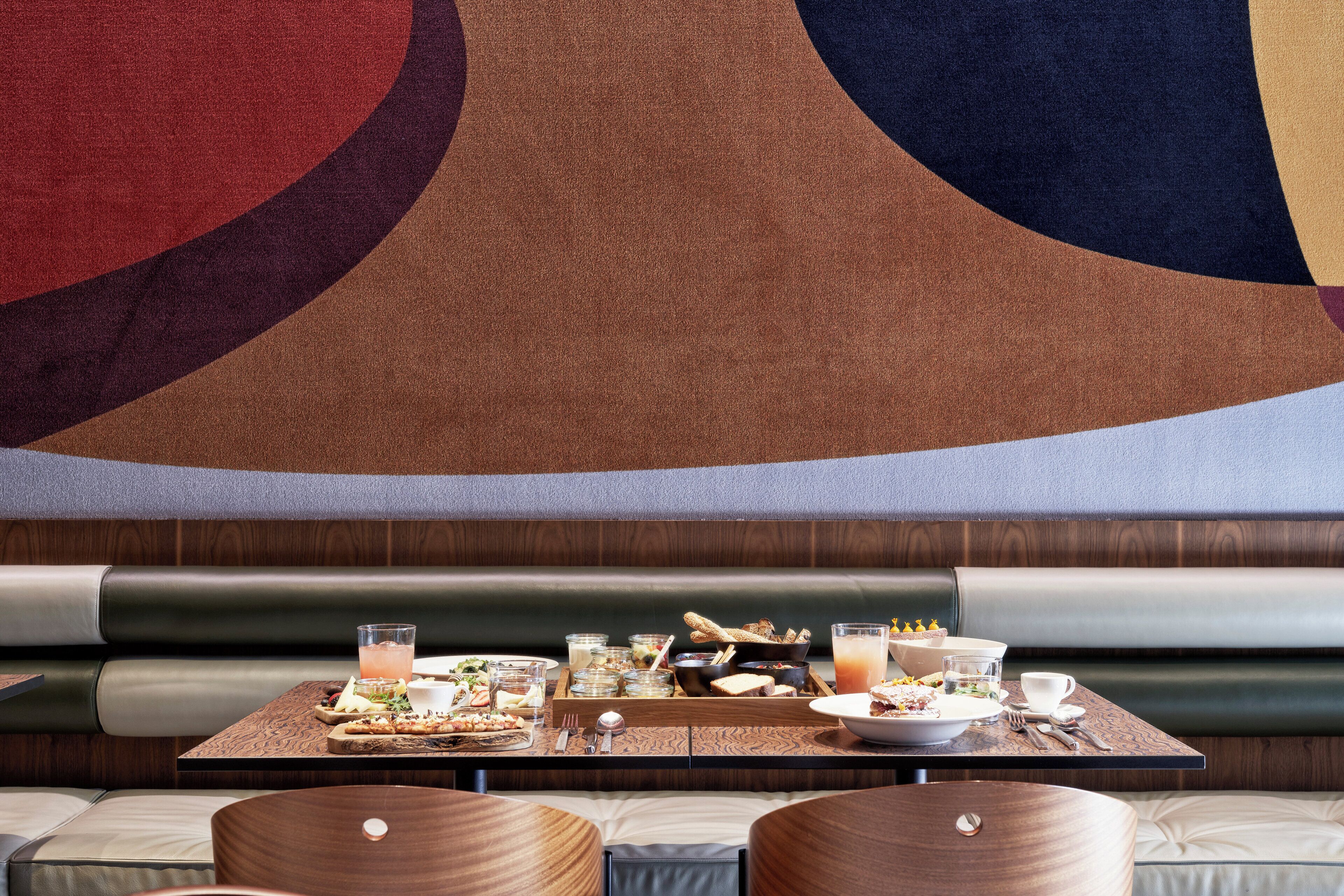 A restaurant booth with a wooden table set for a meal, including plates, glasses, and a variety of dishes.