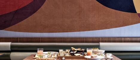 A restaurant booth with a wooden table set for a meal, including plates, glasses, and a variety of dishes.